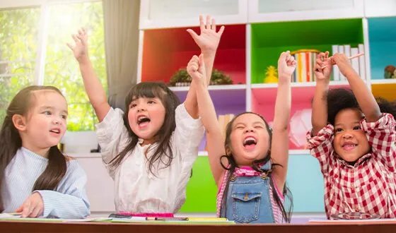 classroom of happy children raising arms