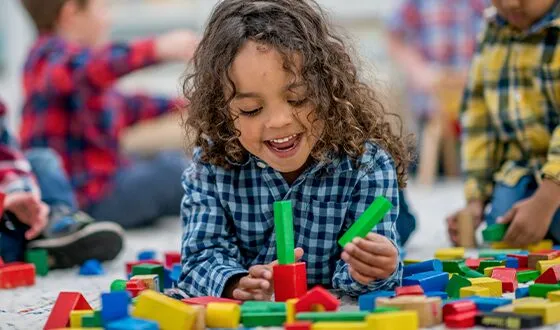 A small child plays with colorful blocks on the floor