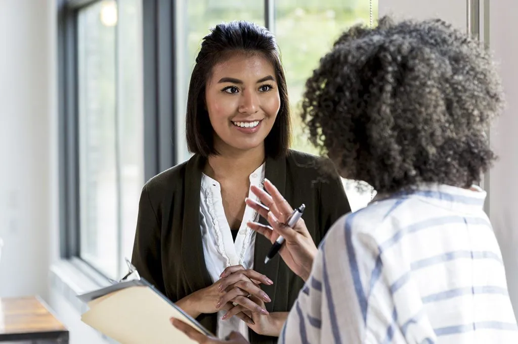 An older teacher gives positive feedback to a newer teacher.