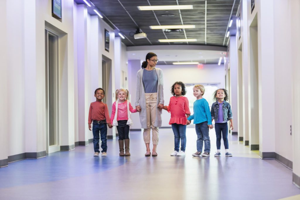 Teacher and preschool students standing in hallway