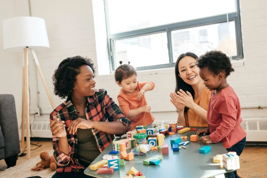 Two teaches sit around a table with young learners