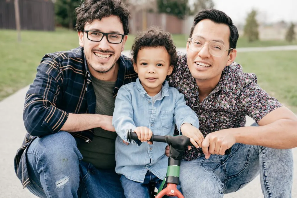 Two dads with toddler son having fun outdoor