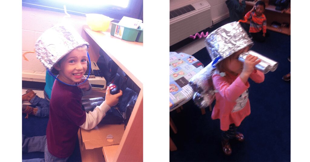 Two young children playing dress-up as astronauts, using ice cream containers covered in tinfoil as helmets.