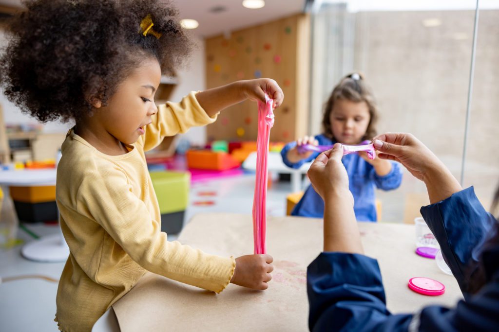 two preschool children engaged in play with slime